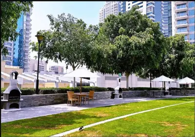 a park with chairs and tables and trees and buildings at Blakely 2BR Lakeview Retreat - Open Balcony and Marina Views in Dubai