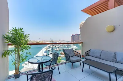 a balcony with a couch and chairs and a view of a harbor at Deluxe Waterfront Unit in Heart Of Dubai Palm Jumeirah in Dubai