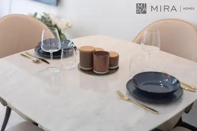 a white table with glasses and plates on it at Mira Holiday Homes - Newly 2 bedroom with balcony in Business Bay in Dubai