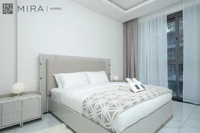 a white bedroom with a large bed and a window at Mira Holiday Homes - Newly 2 bedroom with balcony in Business Bay in Dubai