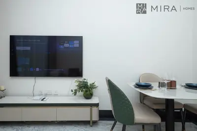 a dining room with a table and a tv on a wall at Mira Holiday Homes - Newly 2 bedroom with balcony in Business Bay in Dubai