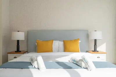 a bedroom with a large white bed with yellow pillows at Beachfront Bliss Luxurious 3-BR Stay in JBR in Dubai