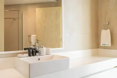 a white bathroom with a sink and a mirror at Beachfront Bliss Luxurious 3-BR Stay in JBR in Dubai