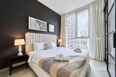 a bedroom with a large bed and a large window at Elegant 2BR Living Steps from Dubai Hills Park in Dubai