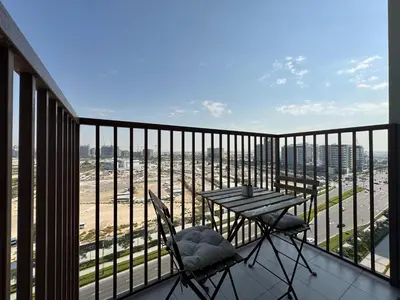 a balcony with a table and chairs and a view of the city at Elegant & Bright 1BR Getaway Near Dubai Hills Park in Dubai