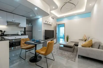 a kitchen and living room with a table and chairs at Dubai Marina - 1BHK Homely Apartment in Dubai