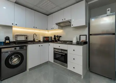 a kitchen with white cabinets and a stainless steel refrigerator at Dubai Marina - 1BHK Homely Apartment in Dubai
