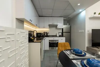 a kitchen with white cabinets and a table and chairs at Dubai Marina - 1BHK Homely Apartment in Dubai