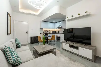 a living room with a couch and a tv and a kitchen at Dubai Marina - 1 BHK Elegant Apartment in Dubai
