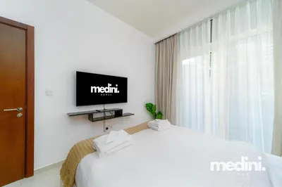 a bedroom with a bed and a tv on a wall at 10 min from Burj Khalifa - Sauna - Gym - Damac Reva in Dubai