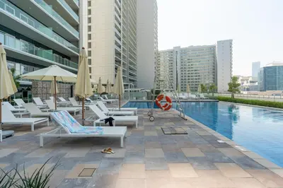 a swimming pool with lounge chairs and a hotel at 10 min from Burj Khalifa - Sauna - Gym - Damac Reva in Dubai