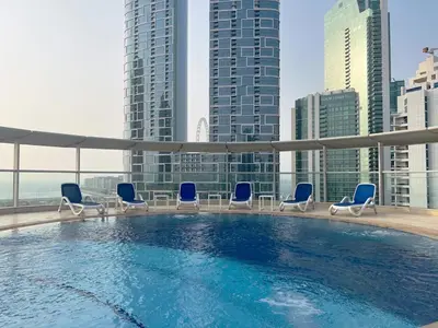 a swimming pool on the roof of a building with chairs at 2 Bedroom Apartment with Spacious Private Garden in Dubai Marina in Dubai