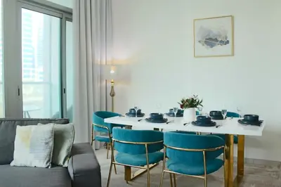 a dining room with a white table and blue chairs at 2 Bedroom Apartment with Spacious Private Garden in Dubai Marina in Dubai