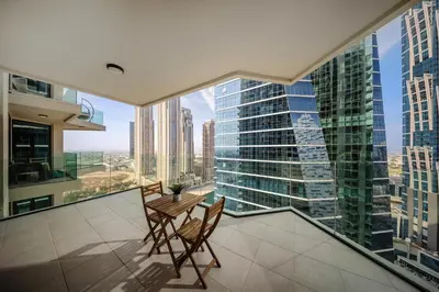 a balcony with a table and chairs and a large window at 2BR apartment in Missoni in Dubai