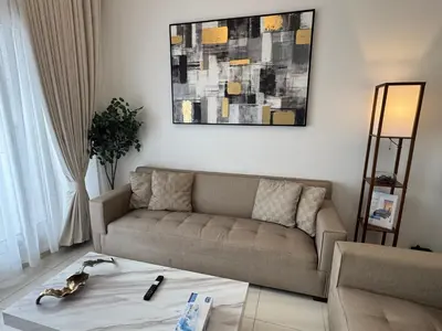 a living room with a couch and a painting on the wall at Silicon Heights II in Dubai
