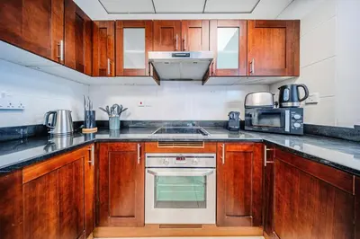 a kitchen with wooden cabinets and a stove top oven at Amazing 1BR apartment near metro station in JLT in Dubai