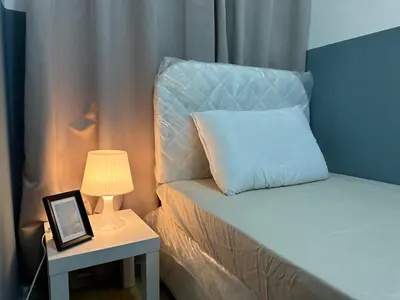 a bed with a pillow next to a table with a lamp at Partition Room with window In Barsha Near Metro in Dubai