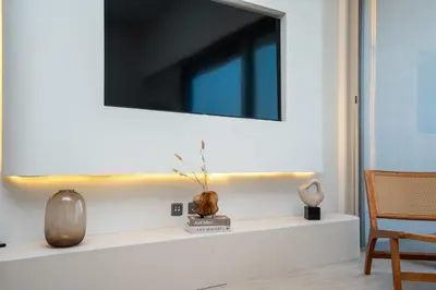 a living room with a television on a white shelf at Modern 1-Bedroom Retreat in MBR City in Dubai