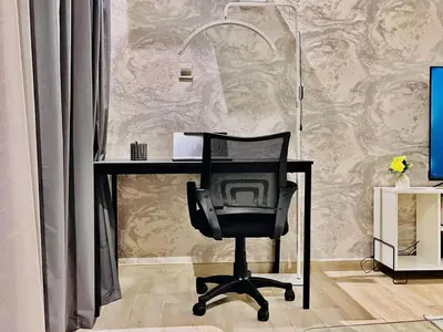 a desk with a chair in front of a wall at Luxuriously Designed Spacious Studio In JVC in Dubai