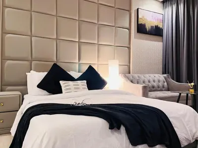 a bedroom with a large white bed and a chair at Luxuriously Designed Spacious Studio In JVC in Dubai