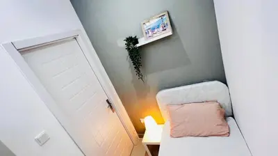 a room with a white door and a chair with a pillow at Compact Partition Room in Barsha in Dubai