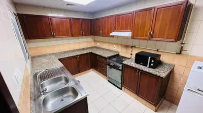a small kitchen with wooden cabinets and a sink at Newly Furnished Room in Barsha 1 Near MOE in Dubai