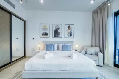 a bedroom with a large white bed and a chair at AWS Holiday Homes - Dreamful Views of the Burj in Dubai