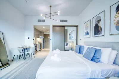 a bedroom with a large white bed with blue pillows at AWS Holiday Homes - Dreamful Views of the Burj in Dubai