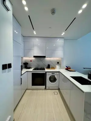 a kitchen with white cabinets and a washing machine at Chic & Modern 1br In Jvc With Full Amenities in Dubai