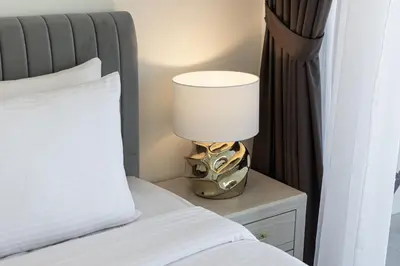 a lamp on a night stand next to a bed at Daniels Stylish 1BR Apartment with Al khail View in Dubai