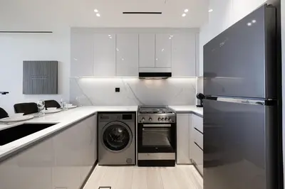 a white kitchen with a washer and a dishwasher at Daniels Stylish 1BR Apartment with Al khail View in Dubai