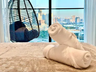 a towel on a bed with a view of a city at New 1br Apt Jvc Pool View, Balcony & Parking in Dubai