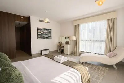 a bedroom with a bed and a chair and a window at Modern Marina Escape 4BR Family Retreat at JBR in Dubai
