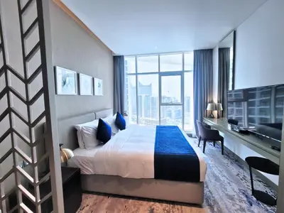 a bedroom with a bed and a desk with a television at Damac Maison Prive - Blue Ocean Holiday Homes in Dubai