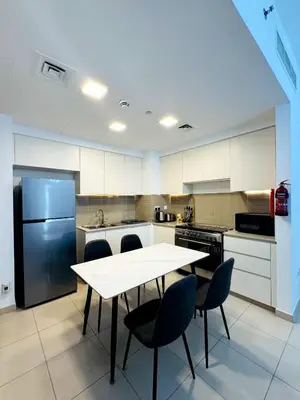 a kitchen with a table and chairs and a refrigerator at 02 Bedroom Apartment in Townsquare in Dubai