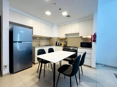 a kitchen with a table and chairs and a refrigerator at 02 Bedroom Apartment in Townsquare in Dubai