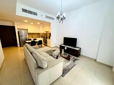 a living room with a couch and a tv and a table at 02 Bedroom Apartment in Townsquare in Dubai