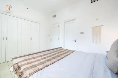 a white bedroom with a bed with a striped blanket on it at Cozy Old Town 2-Bed Apartment with Burj Khalifa Views 202RH-2 in Dubai