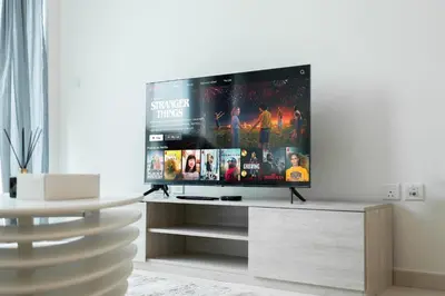 a flat screen tv sitting on a stand in a living room at 1BR Palm Jumeirah - Rooftop Pool & Beach Access in Dubai