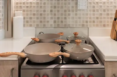 three pots on top of a stove in a kitchen at 1BR Palm Jumeirah - Rooftop Pool & Beach Access in Dubai