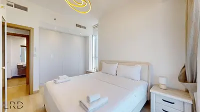 a bedroom with a white bed with two towels on it at Spacious 3BR Apartment in Dubai