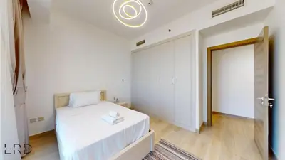 a white bedroom with a bed and a door at Spacious 3BR Apartment in Dubai