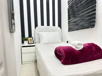 a white bed with a purple pillow on it at Partitioned Single Room in Al Barsha 1 Near Metro in Dubai