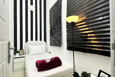 a bedroom with a bed with a red pillow and a lamp at Partitioned Single Room in Al Barsha 1 Near Metro in Dubai