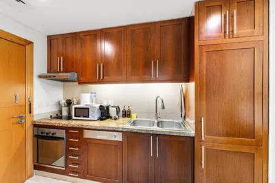 a kitchen with wooden cabinets and a sink and a microwave at Cozy Studio with Scenic Canal Views in Dubai