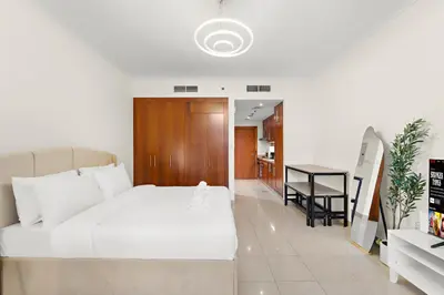 a bedroom with a white bed and a kitchen at Cozy Studio with Scenic Canal Views in Dubai