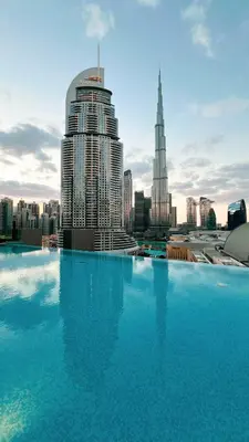 a large swimming pool with a view of a city at Luxe 1BR with Full Burj Views and Dubai Mall Access in Dubai