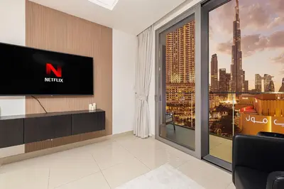 a living room with a tv and a large window at Luxe 1BR with Full Burj Views and Dubai Mall Access in Dubai