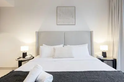 a bedroom with a large white bed with two lamps at Luxe 1BR with Full Burj Views and Dubai Mall Access in Dubai