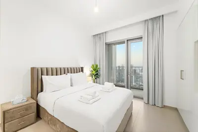 a white bedroom with a large bed and a large window at Elegant 2BR in Downtown Dubai l Walk to Dubai Mall in Dubai